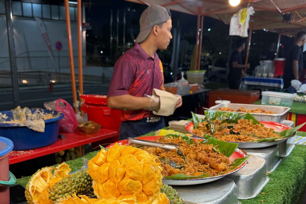 Hawker stall cook preparing nasi lemak and local dishes at a Singapore food centre