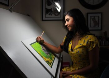 A Singapore illustrator works at her table during the illustration arts fest, surrounded by hand-drawn prints on display