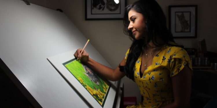 A Singapore illustrator works at her table during the illustration arts fest, surrounded by hand-drawn prints on display