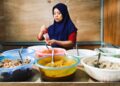 A Peranakan cuisine cook presents traditional nyonya dishes at a heritage restaurant table in Singapore