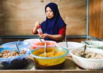 A Peranakan cuisine cook presents traditional nyonya dishes at a heritage restaurant table in Singapore
