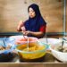 A Peranakan cuisine cook presents traditional nyonya dishes at a heritage restaurant table in Singapore