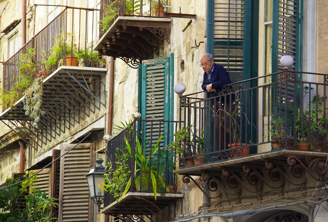 A gardener managing a small compost tumbler on a Singapore balcony as part of a sustainable rewilding routine.