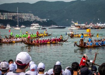 A team of paddlers competing in June festivals Singapore dragon boat races at Bedok Reservoir, drums beating .