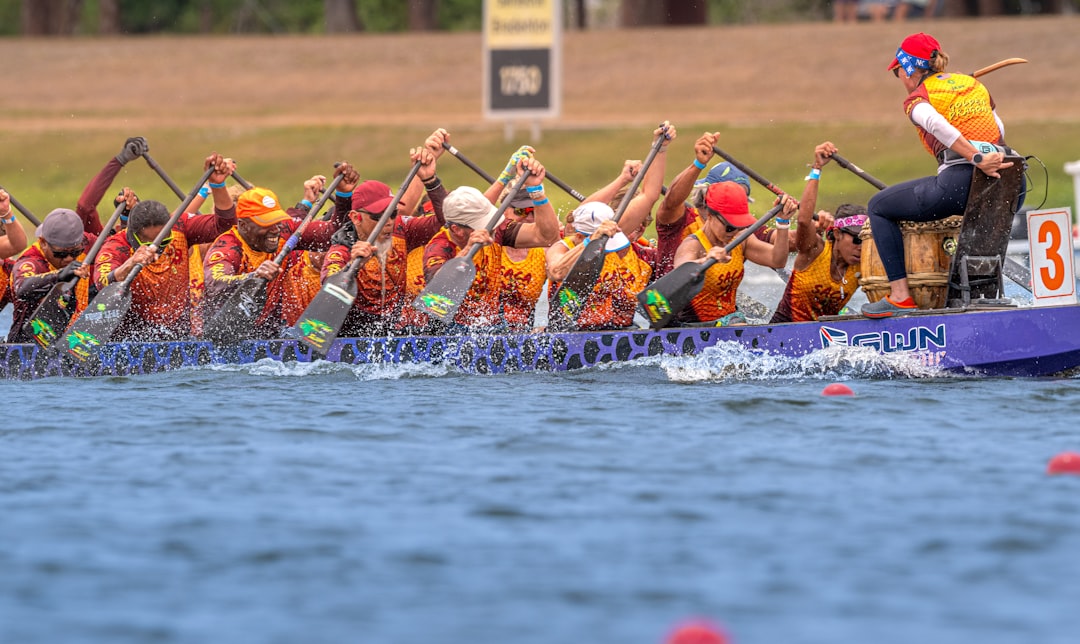A dragon boat team raising their paddles together after crossing the finish line at a Singapore race