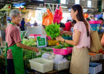 Elderly hawker serves at a traditional Singapore hawker centre,representing one of the city's most enduring Singapore rituals