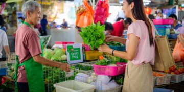 elderly-hawker-stall-singapore-unsplash - SINwebzine Elderly hawker serves at a traditional Singapore hawker centre,representing one of the city's most enduring Singapore rituals