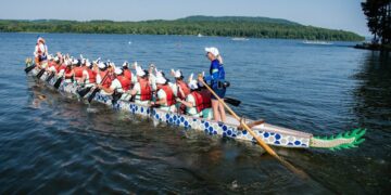 scottsboro-dragon-boat-e1752771612146 - SINwebzine A crew of paddlers competing in a dragon boat race on a calm Singapore reservoir at dawn