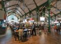 A smiling traveller enjoys a budget getaway meal at a busy Singapore hawker centre