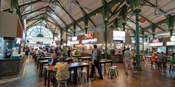traveller-eating-hawker-centre-singapore-unsplash - SINwebzine A smiling traveller enjoys a budget getaway meal at a busy Singapore hawker centre