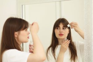 A woman applying a Singapore beauty brand botanical serum to her face in a bright tropical setting