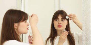 A woman applying a Singapore beauty brand botanical serum to her face in a bright tropical setting