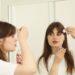 woman-applying-serum-unsplash - SINwebzine A woman applying a Singapore beauty brand botanical serum to her face in a bright tropical setting