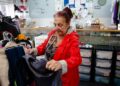 A woman carefully inspects a rack of preloved garments while thrifting designer pieces in a Singapore vintage shop
