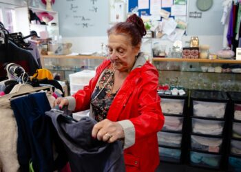 A woman carefully inspects a rack of preloved garments while thrifting designer pieces in a Singapore vintage shop