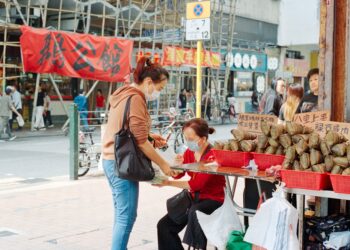 A woman selecting rice dumplings at a Singapore market stall during Dragon Boat Festival season