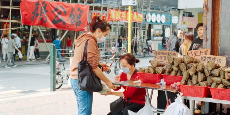 A woman selecting rice dumplings at a Singapore market stall during Dragon Boat Festival season