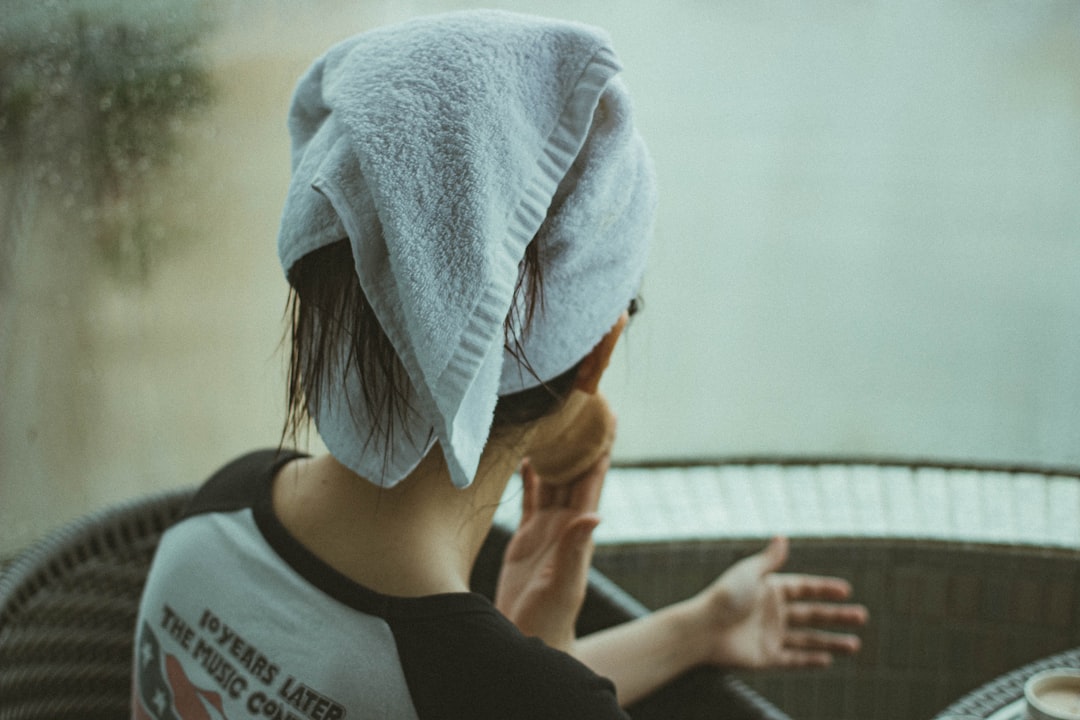 A woman gently blotting her hair dry with a microfiber towel, a key step in any monsoon beauty routine for humid climates