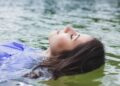 A woman resting peacefully inside a float therapy pod in a Singapore wellness studio, eyes closed in deep relaxation.
