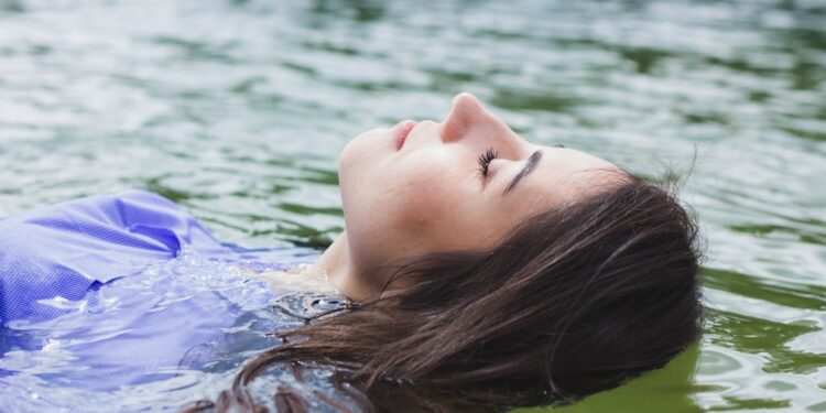 woman-relaxing-float-pod-unsplash - SINwebzine A woman resting peacefully inside a float therapy pod in a Singapore wellness studio, eyes closed in deep relaxation.