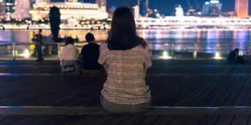 woman-walking-marina-bay-night-lights-unsplash - SINwebzine strolling the Marina Bay waterfront during June events in Singapore, surrounded by glowing light installations at night