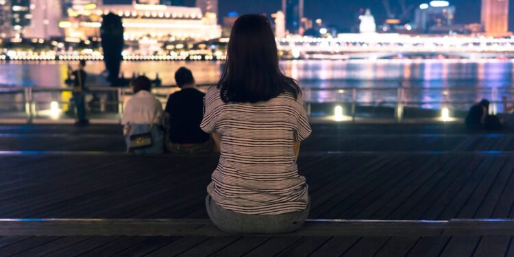woman-walking-marina-bay-night-lights-unsplash - SINwebzine strolling the Marina Bay waterfront during June events in Singapore, surrounded by glowing light installations at night