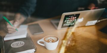 work-coffee-unsplash - SINwebzine A diaspora entrepreneur works at a centre cafe, illustrating the hustle of diaspora entrepreneurs building a businesses