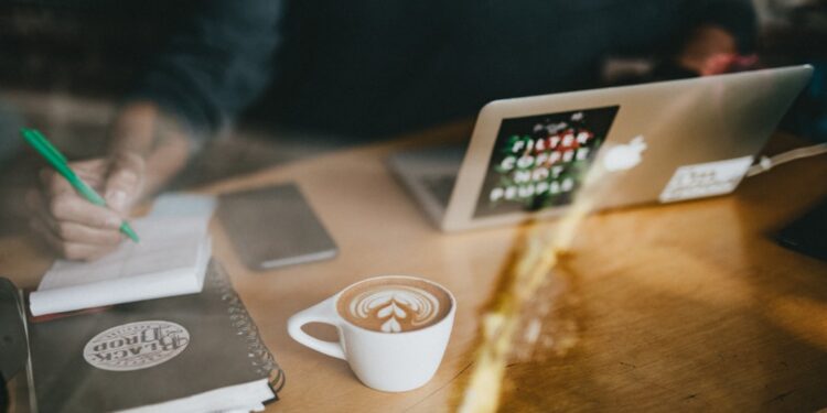 work-coffee-unsplash - SINwebzine A diaspora entrepreneur works at a centre cafe, illustrating the hustle of diaspora entrepreneurs building a businesses