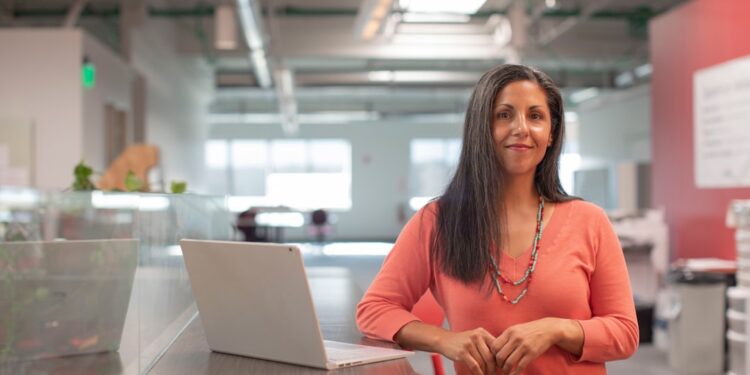 business-woman-office-unsplash - SINwebzine A financial advisor in Singapore reviews MAS policy documents with a client at her desk in a downtown office building.