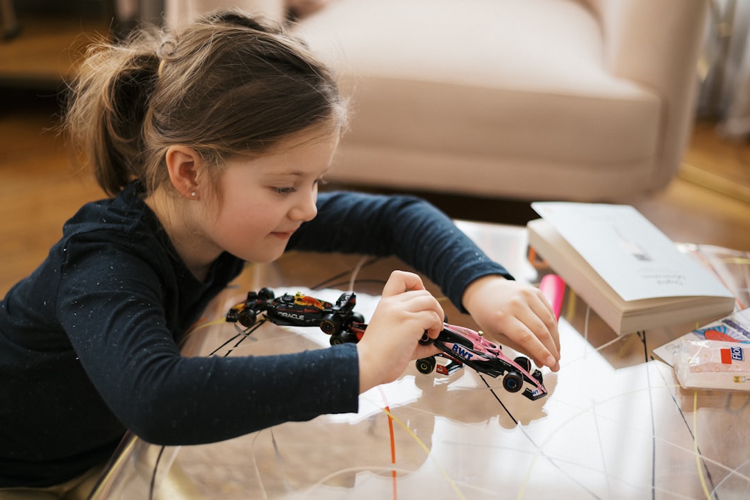 A girl assembling a small robot during a STEM-based science workshop, with an educator guiding the session in the background.