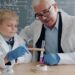 A child conducting hands-on science workshops at a classroom table wearing safety goggles and mixing colourful liquids.