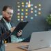 founder-laptop-office-unsplash - SINwebzine A first-time founder reviewing Singapore grants on a laptop in a Singapore co-working office
