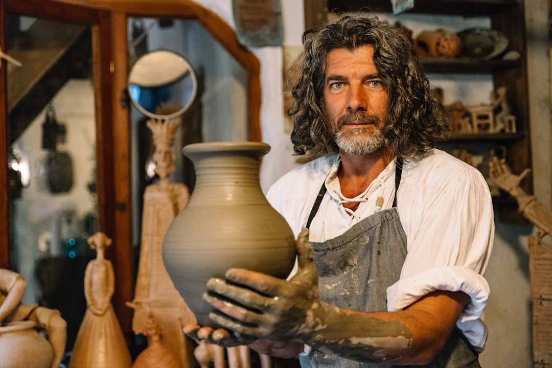 A man holds his finished glaze-fired piece outside a Singapore ceramic studios class, smiling at the bowl he made