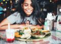 singaporean-woman-eating-hawker-food-unsplash - SINwebzine A Singaporean expat woman shares a meal at an outdoor hawker-style food stall, connecting community through food abroad