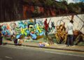 A young person painting a large street art mural on an outdoor wall during a Singapore youth programme