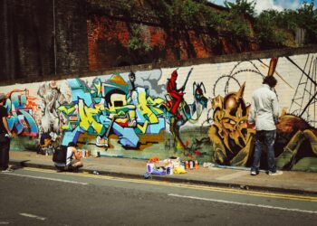 A young person painting a large street art mural on an outdoor wall during a Singapore youth programme