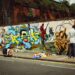 A young person painting a large street art mural on an outdoor wall during a Singapore youth programme