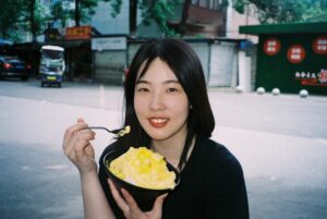 A woman enjoying a bowl of laksa at a busy Singapore hawker centre stall