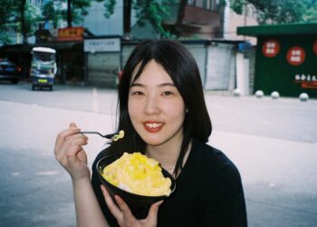 A woman enjoying a bowl of laksa at a busy Singapore hawker centre stall