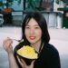 A woman enjoying a bowl of laksa at a busy Singapore hawker centre stall