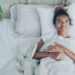A woman lying awake in a warm Singapore bedroom, struggling with July humidity and poor sleep