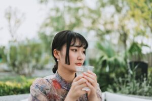 A professional woman beginning her morning routine in Singapore by drinking water at sunrise before the heat builds