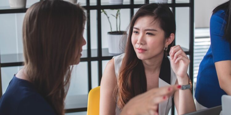 asian-woman-job-interview-office-unsplash - SINwebzine A professional woman in a Singapore office reviews documents during the city's August hiring surge