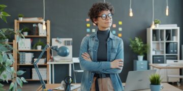 foreign-entrepreneur-standing-in-office-unsplash - SINwebzine A foreign founder reviews documents at a desk while setting up a Singapore company remotely