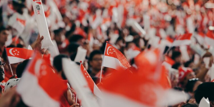 national-day-parade-singapore-unsplash - SINwebzine A crowd of Singaporeans cheering together inside a stadium during the National Day Parade, dressed in red and white