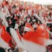 national-day-parade-singapore-unsplash - SINwebzine A crowd of Singaporeans cheering together inside a stadium during the National Day Parade, dressed in red and white