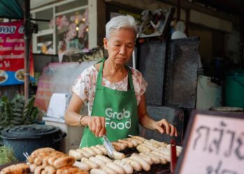 A woman enjoying a plate of food at a Singapore vegetarian hawker stall in a busy food centre