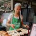 woman-eating-hawker-centre-singapore-unsplash - SINwebzine A woman enjoying a plate of food at a Singapore vegetarian hawker stall in a busy food centre