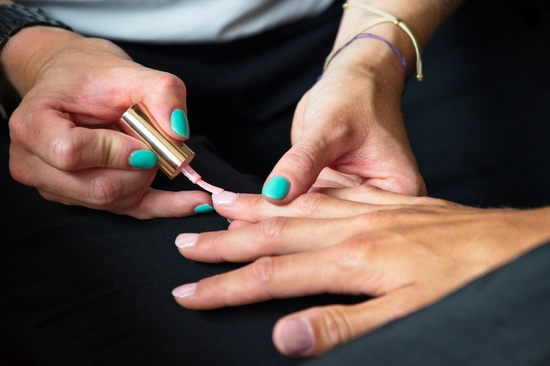 A client applies cuticle oil to maintain her manicure between visits to her Singapore nail studio.