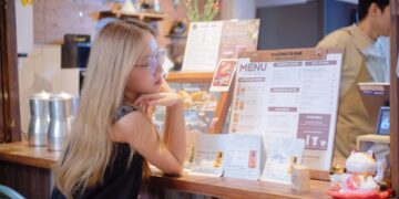 woman-reading-restaurant-menu-unsplash - SINwebzine A woman carefully reviews a buffet menu at a Singapore National Day celebration, making informed gluten-free choices